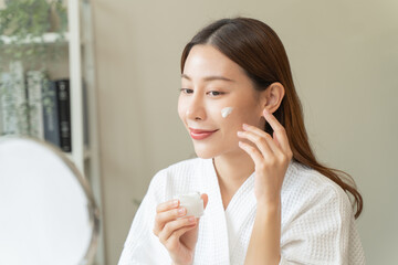 Effortless Elegance: A Serene Moment of Self-Care as a Woman Applies Luxurious Moisturizing Cream...