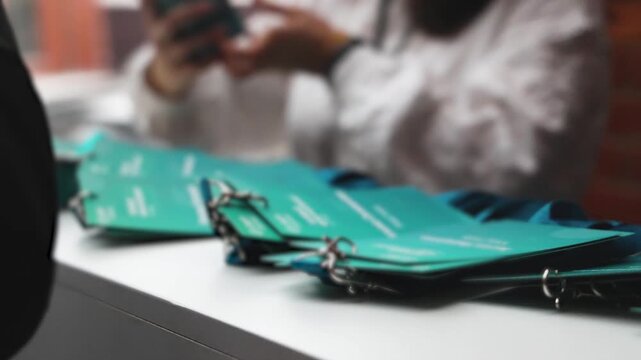 Checking in on conference congress forum event, registration desk table, visitors attendees register electronic ticket and receiving blue lanyard with name green badge and entry wristband bracelet
