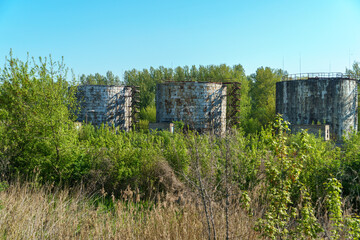 A large modern plant located near a wheat field for the storage and processing of grain crops. view of the granary illuminated by the light of the setting sun against the blue sky. harvest season.