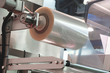 Automatic polyethylene plastic bag production machine with lighting effect. Close-up of the roller of the plastic bag production machine in the light blue scene. product packaging concept.