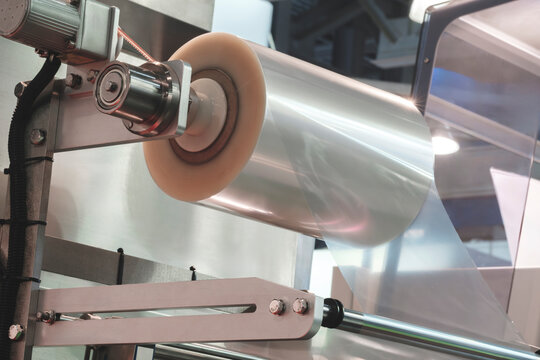 Automatic polyethylene plastic bag production machine with lighting effect. Close-up of the roller of the plastic bag production machine in the light blue scene. product packaging concept.