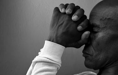 praying to god with hands together portrait view of Caribbean man praying with black background with people stock photo stock image	