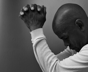 praying to god with hands together portrait view of Caribbean man praying with black background with people stock photo stock image	