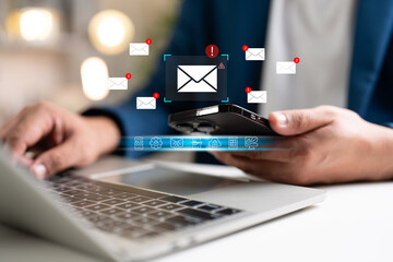 A Businessman working on a laptop, mobile phone open an email caution warning sign for notification error and maintenance concept, network security, computer virus detected, personal data protection.