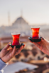 A woman's and a man's hands holding glasses of Turkish tea