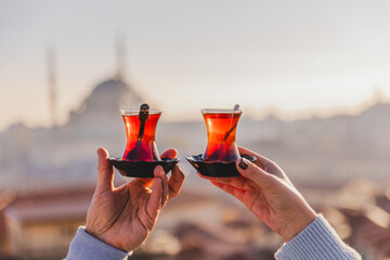 A woman's and a man's hands holding glasses of Turkish tea