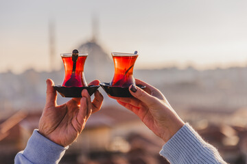 A woman's and a man's hands holding glasses of Turkish tea