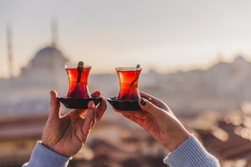 A woman's and a man's hands holding glasses of Turkish tea