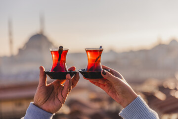 A woman's and a man's hands holding glasses of Turkish tea