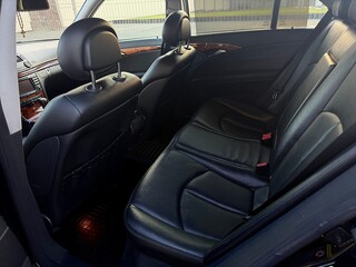 Black leather rear seats of a luxury sedan with wooden trim. Clean interior of a premium vehicle featuring comfortable passenger seating and classic design