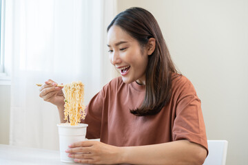 Happy temptation, attractive asian young student woman, cute girl using chopsticks eating instant ramen, noodles soup from a cup, cooking meal fast food lifestyle of traditional japanese person.