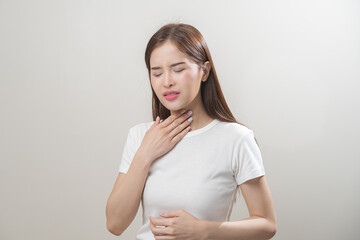 Obraz premium Sickness in inflaming asian young woman, girl use hand check self touch at sore throat, pain thyroid gland on neck or disease reflux, acid of suffer people on wall background. Medical and healthcare.