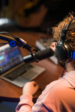 Cheerful young man recording podcast in studio. Confident man with headphones and microphone recording a podcast. Happy guy talking on web radio.