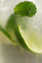 Plastic cup with lime and mint drink in sunlight close up