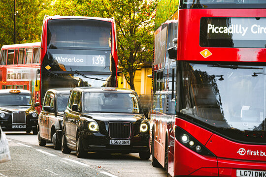 Red Double-Decker First Bus Public Transport Company Vehicle, LEVC Black Cab Taxi Electric Vehicles, Selfridges Oxford Street, Central London, England, United Kingdom &mdash; 1 November 2025