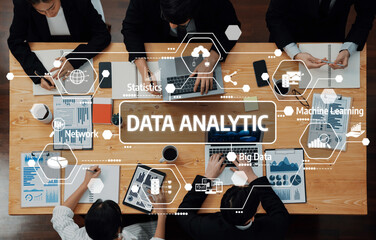 A diverse team engages in data analytic discussions, utilizing charts and technology to drive insights and decisions in a modern office setting. Amity