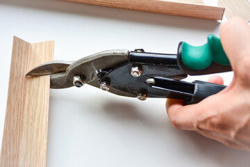 metal shears cutting a wooden trim. interaction between the industrial tool and the wooden material, precision of the cutting process. for DIY guides, woodworking tutorials, instructional content