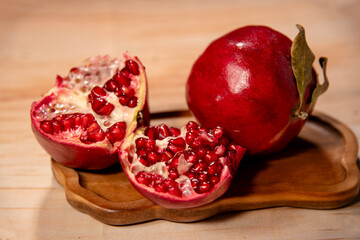 Pomegranates and their seeds on a wooden stand