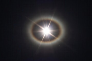 Radiant sun with prominent optical halo phenomenon and dramatic starburst lens flare effect