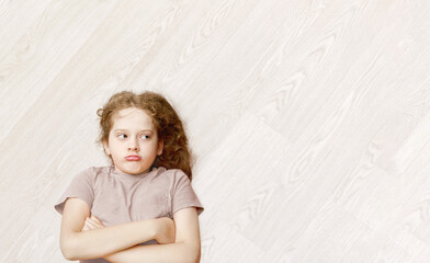 Sad little girl  lying at laminate or parquet, wooden  floor.