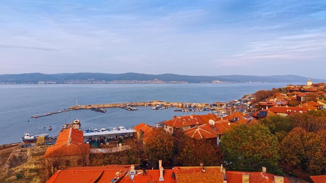 Red tiled roofs of the houses in the coastal park of Nessebar, Bulgaria. Approaching the quay with a berth and multiple boats and yachts.