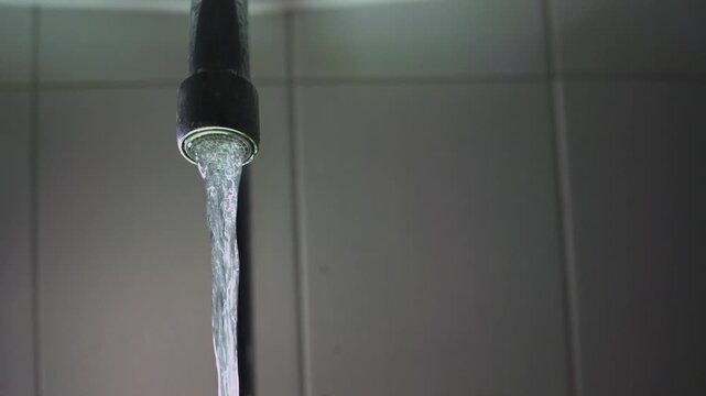 Water pouring from a faucet aerator close-up of a bathroom