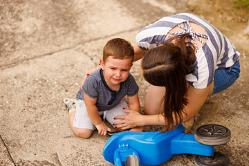 Mother comforting crying son after falling off the bike