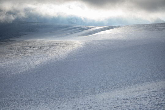 Minimal alpine glacier with snow and low clouds