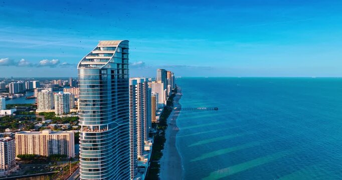 Modern high-rises standing in row on the shore of the Atlantic Ocean. Bright sun lights the cityscape of Miami, Florida, USA. Drone footage.