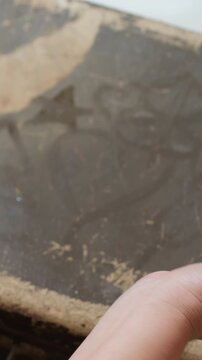caucasian grandmother hand tracing dusty trunk closeup, wrinkled fingers with wedding ring exploring faded pattern and patina, gentle inspection like restorer, archivist and storyteller moments, quiet