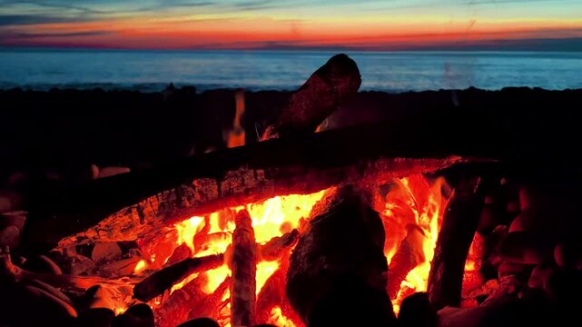 A campfire on the Black Sea coast in Tuapse. A campfire built on pebbles. A picnic at night by the sparkling logs of a campfire. A sunset on the slope of the Caucasus Mountains. 4К