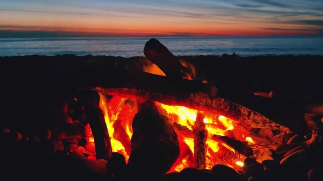 A campfire on the Black Sea coast in Tuapse. A campfire built on pebbles. A picnic at night by the sparkling logs of a campfire. A sunset on the slope of the Caucasus Mountains. 4К