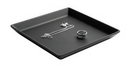 Black textured square jewelry tray with silver necklace and ring isolated on transparent background