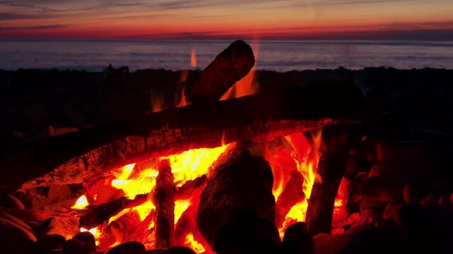 A campfire on the Black Sea coast in Tuapse. A campfire built on pebbles. A picnic at night by the sparkling logs of a campfire. A sunset on the slope of the Caucasus Mountains. 4К