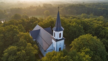 Aerial view of a charming church nestled in a dense forest at sunrise