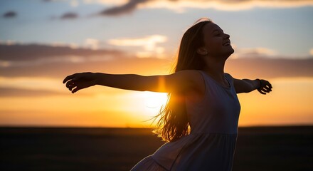 A young woman stands in a field at sunset with arms outstretched, embodying freedom and joy. This inspiring shot is perfect for wellness ads, travel blogs, or motivation projects.