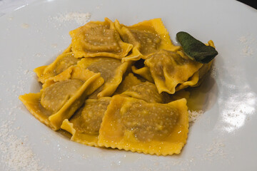 Delicious plate of tortelli di zucca with sage on a white plate.