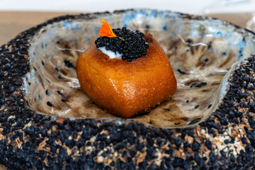 Gourmet dish with caviar and edible flower served in a unique ceramic bowl