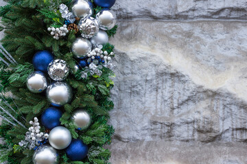 Spruce branches with blue and silver balls on a stone background. Copy space.