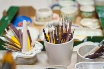 Various professional art brushes of different shapes and sizes in containers on a studio table.