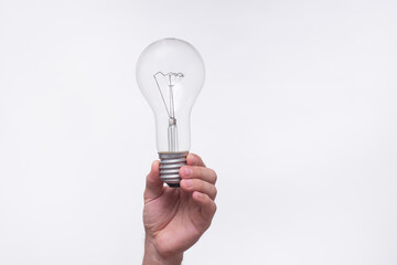 human hand holds classic incandescent light bulb against white background. show transparent glass and filament. Close-up of hand presenting traditional light bulb, symbolizing ideas, creativity.