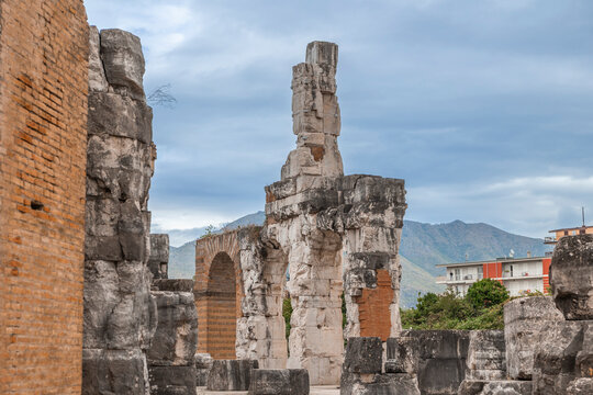 Ancient Roman ruins of the Capua Amphitheater with mountain backdrop and modern architecture contrast