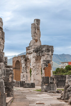 Ancient Roman ruins of the Capua Amphitheater with mountain backdrop and modern architecture contrast
