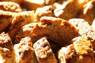 Close-up detail of homemade traditional Italian almond biscuits called Cantucci or Biscotti illuminated by warm sunlight on a baking tray