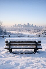 Snow-covered bench facing winter city skyline at sunrise