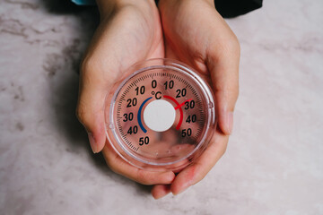 Thermometer held in hands showing temperature in Celsius with red and blue indicators, symbolizing warmth and cold sensation