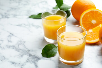Fresh orange juice and fruits on white marble table, closeup. Space for text