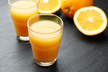 Fototapeta premium Fresh orange juice and fruits on black table, closeup