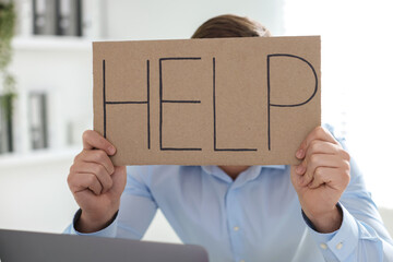Man holding sign with word Help in office