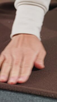 brown fleece on table caucasian hands smoothing pattern paper, home tailor aligning white template, tactile fabric inspection, soft texture closeup, precise edge smoothing, cozy studio lighting,